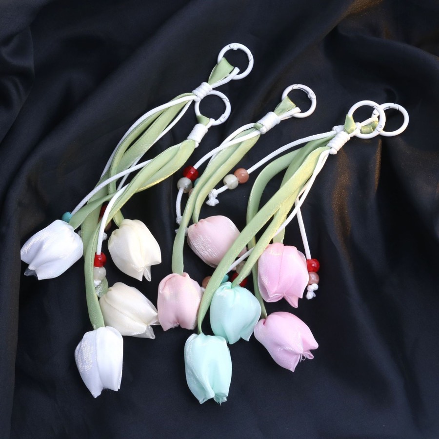 Pastel tulip fabric keychains arranged on black satin