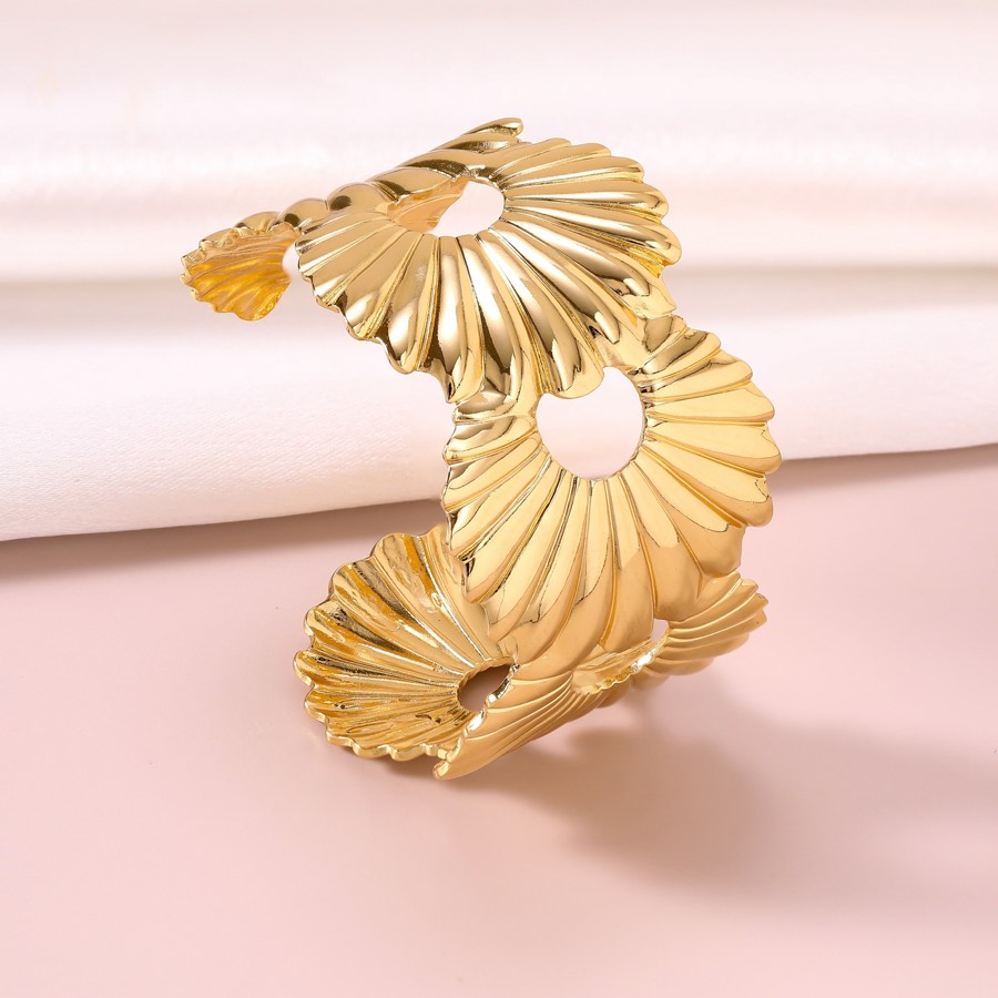 Gold sculptural open bangle on a blush background